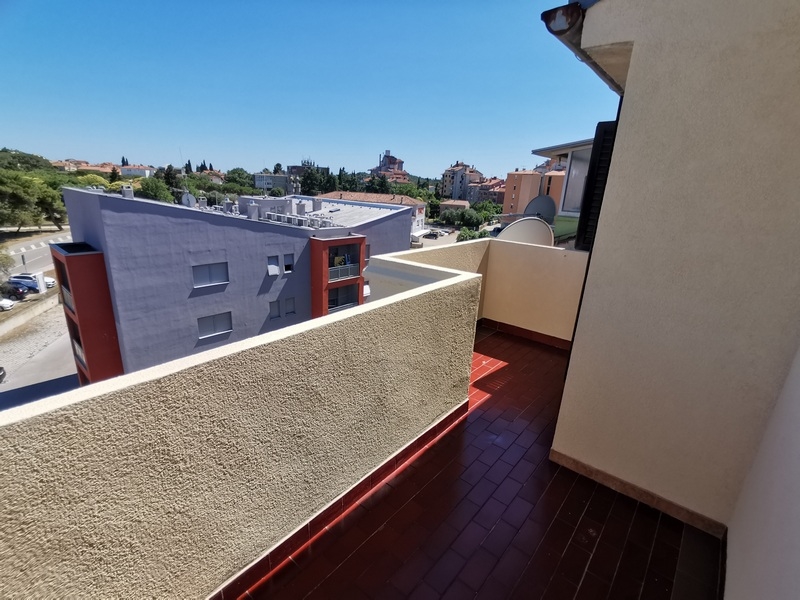 Balcone stretto con pavimento rosso sopra le case vicine