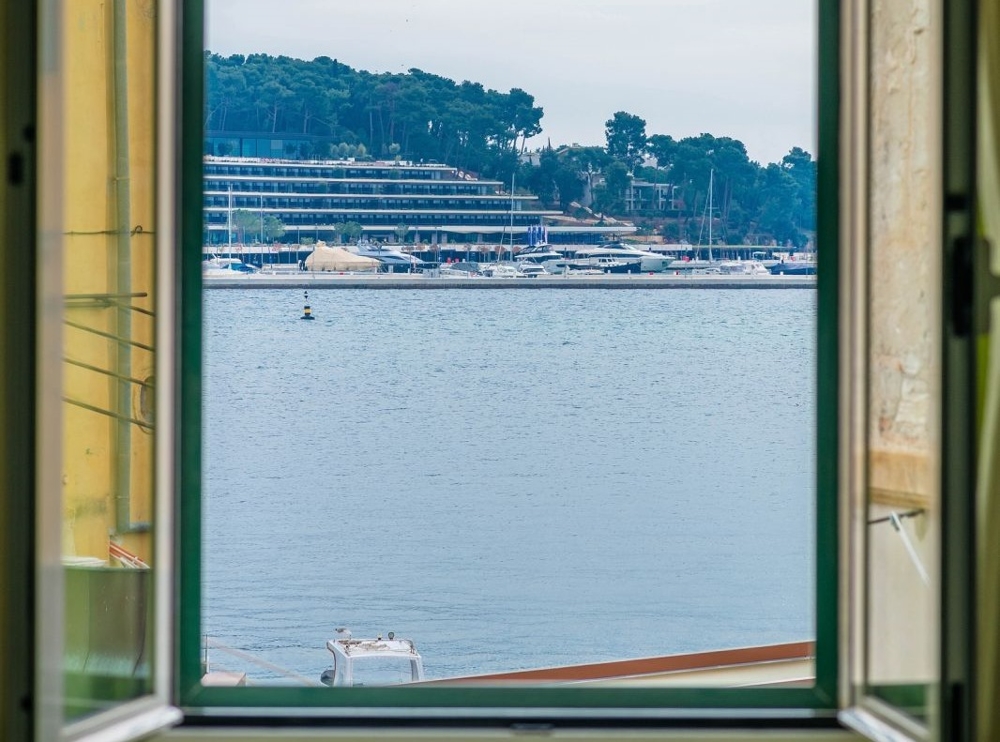 Vista dalla finestra sul porto di Rovinj con barche a vela