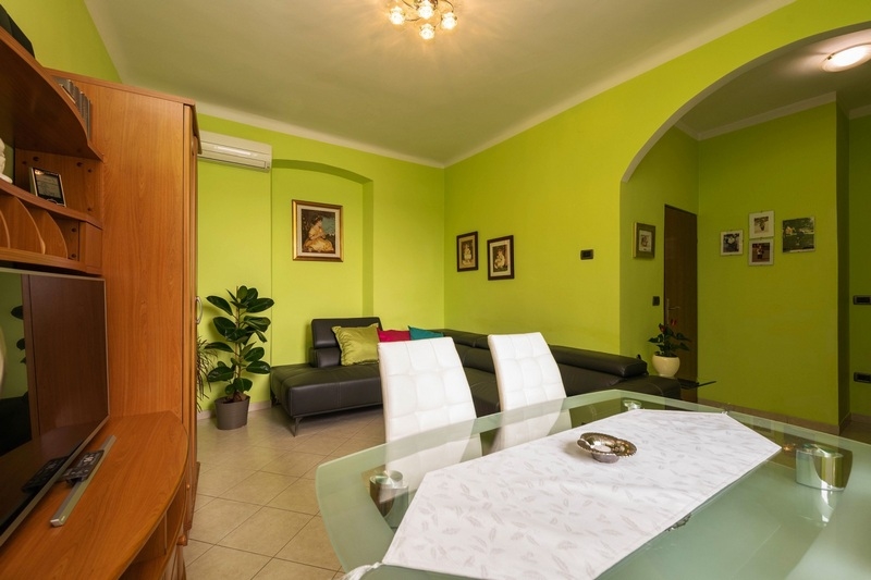 Soggiorno con parete verde e angolo salotto bianco a Rovinj