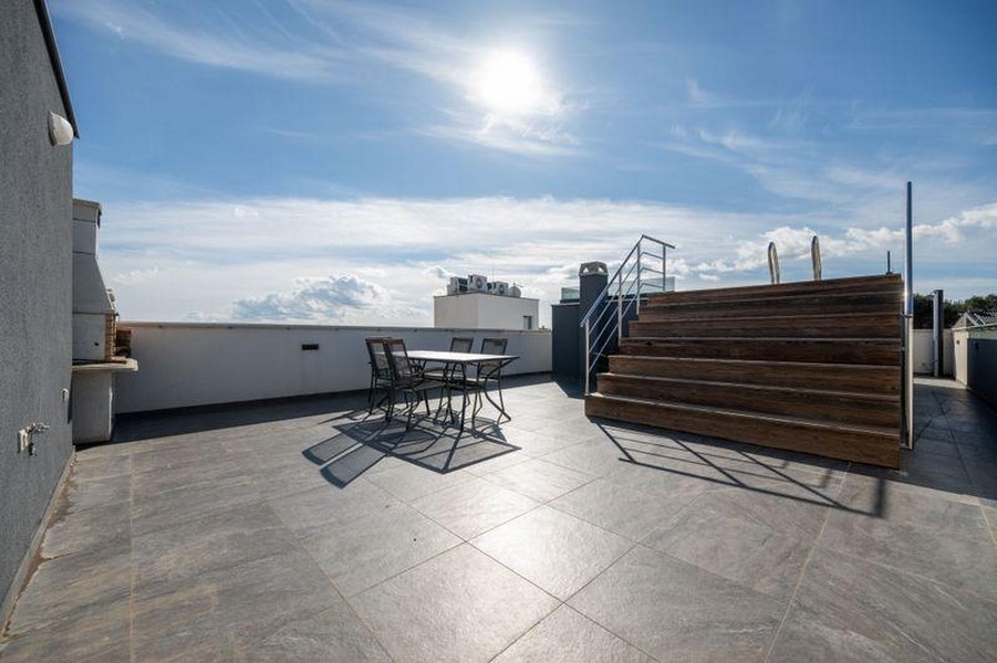 Grande terrazza sul tetto con zona seduta e deck in legno