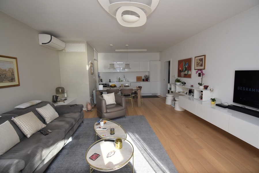 Zona giorno con divano, cucina aperta e TV