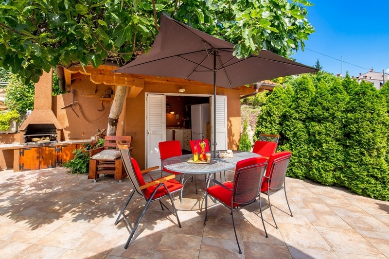 Terrazza con set di sedie rosse sotto il fico