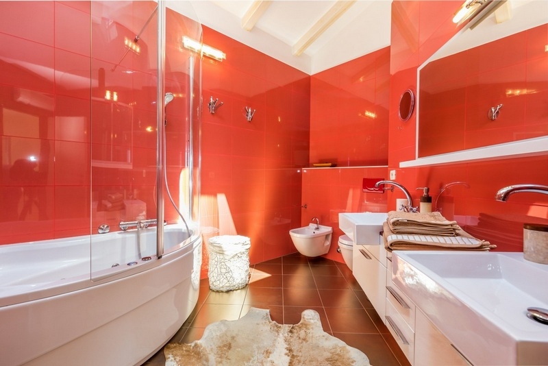 Bagno in rosso intenso con vasca ad angolo e doppio lavabo