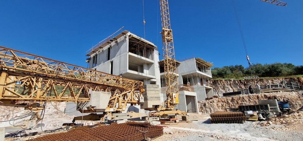 Cantiere con gru e strutture al grezzo sul pendio