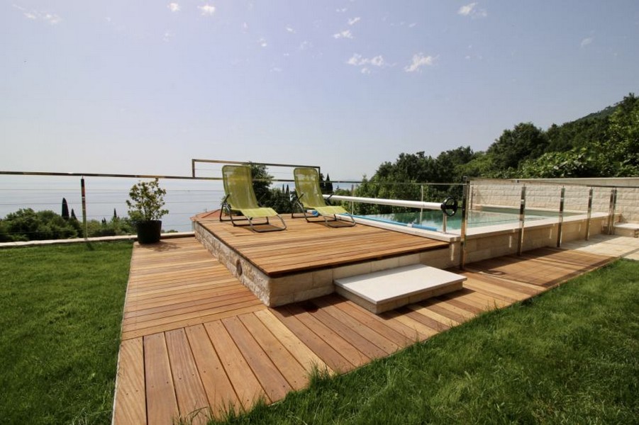 Deck in legno con lettini a bordo piscina sopra il mare