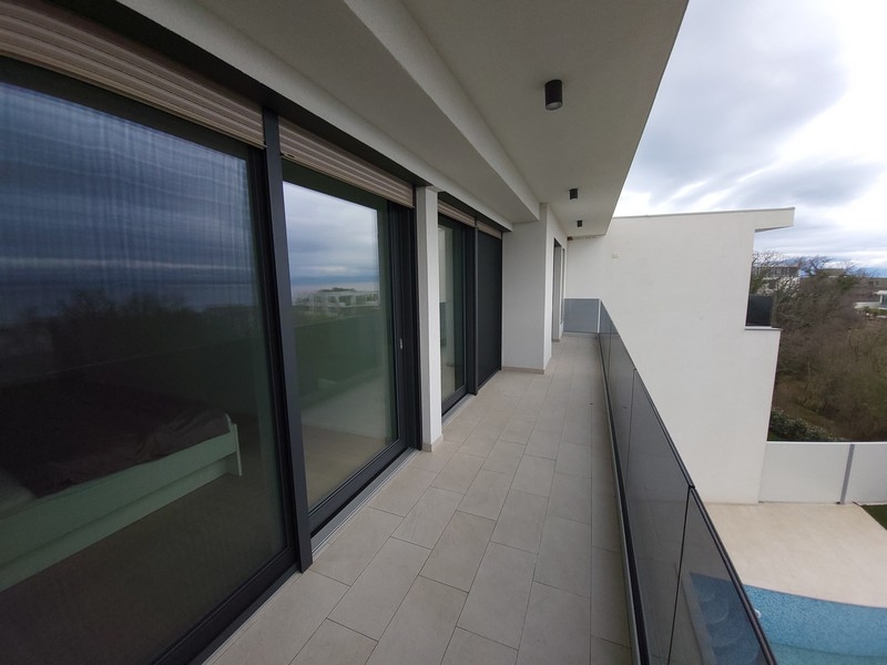 Terrazza perimetrale con ringhiera in vetro e finestre a tutta altezza