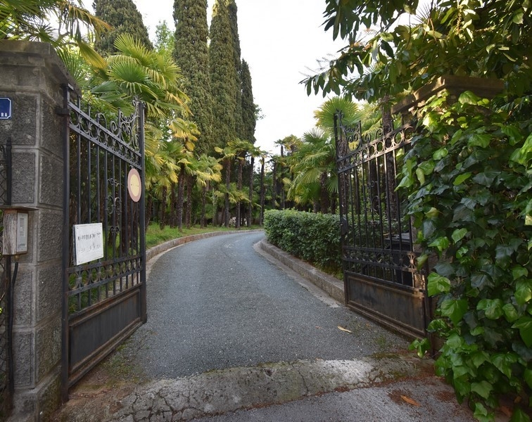 Cancello in ferro battuto verso l'accesso tra i cipressi