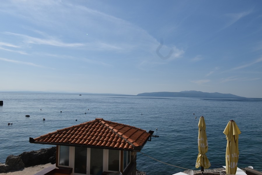 Casa sulla spiaggia con tetto di tegole e ombrelloni sull'acqua