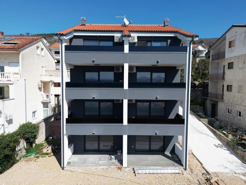 Edificio nuovo con tetto di tegole e balconi scuri visto da dietro