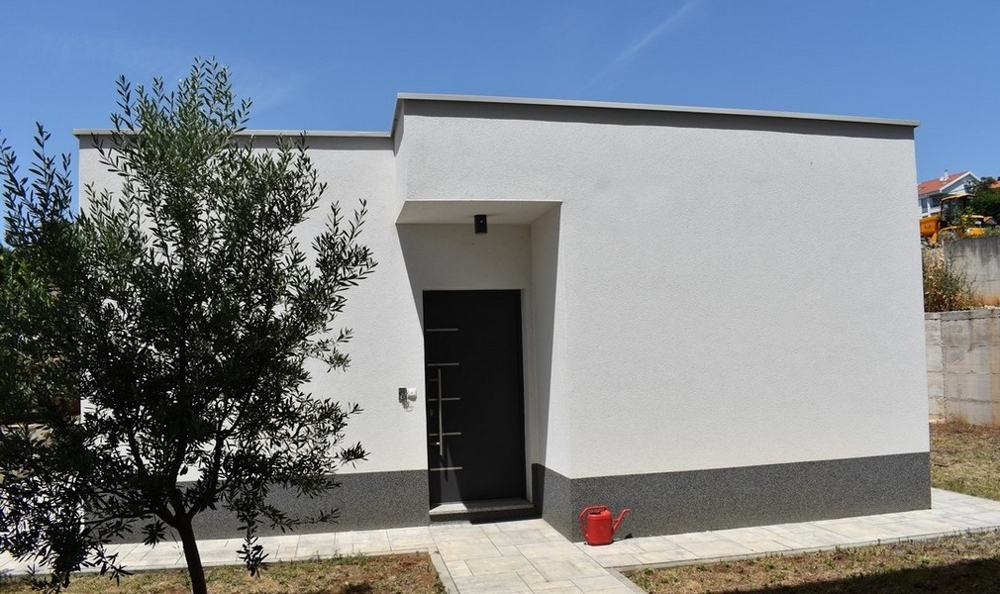 Basso edificio annesso con porta d'ingresso scura in giardino