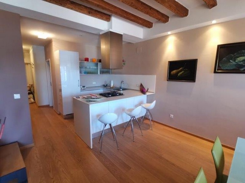 Cucina lineare con bancone e sgabelli sotto le travi di legno