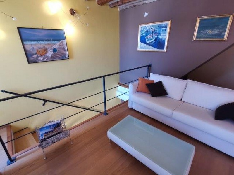 Zona giorno con divano bianco e quadri alle pareti a Rovinj