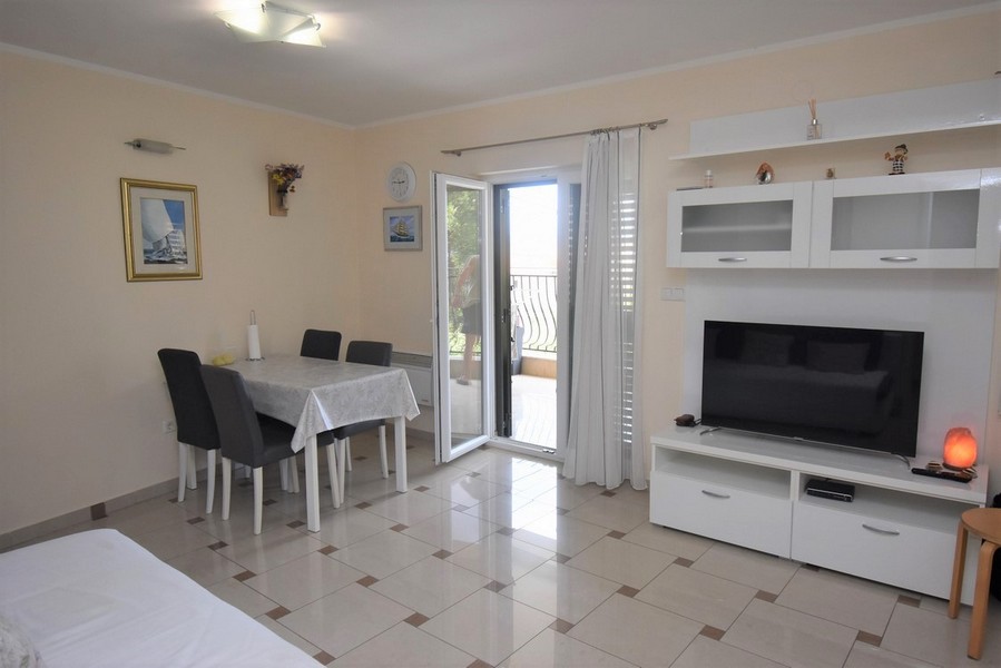 Zona giorno con tavolo, TV e porta della terrazza