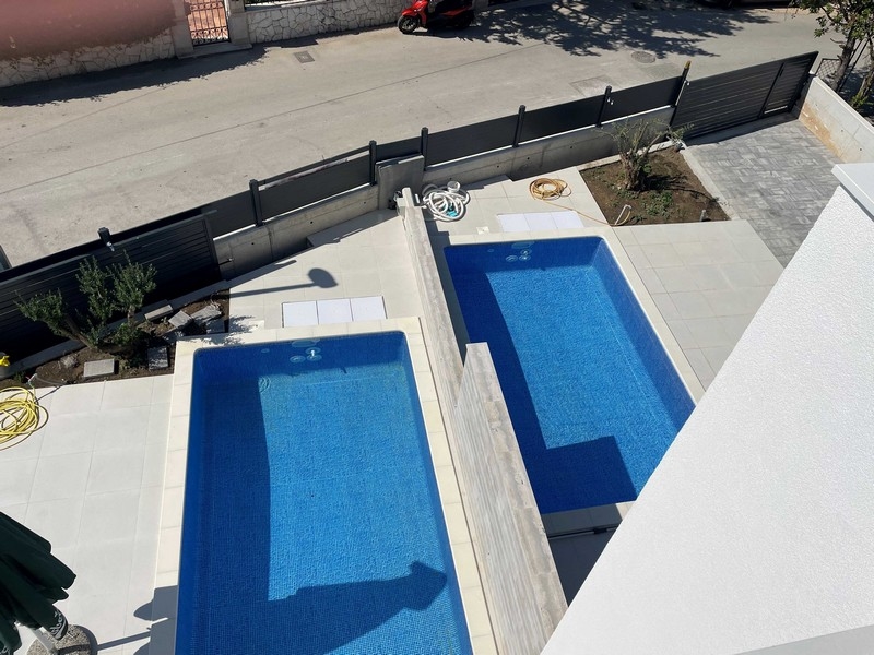 Due piscine affiancate viste dall'alto con ulivo accanto