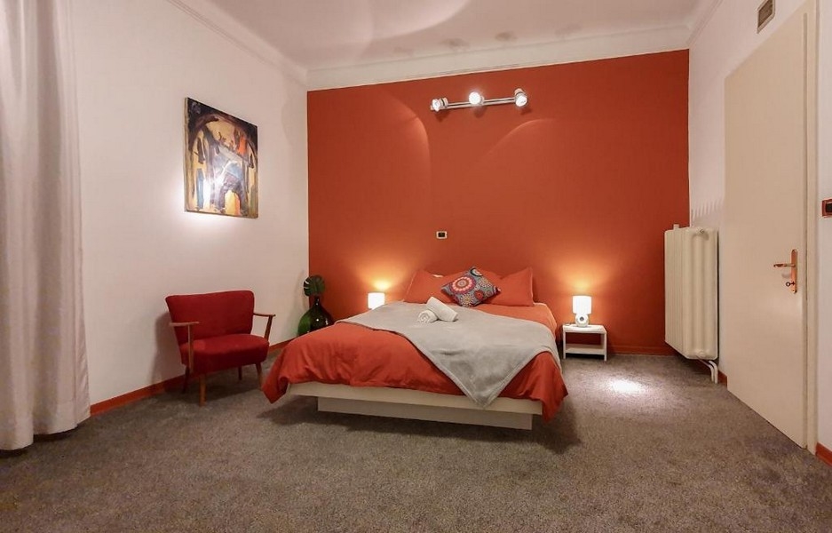 Camera da letto con parete rossa e poltrona