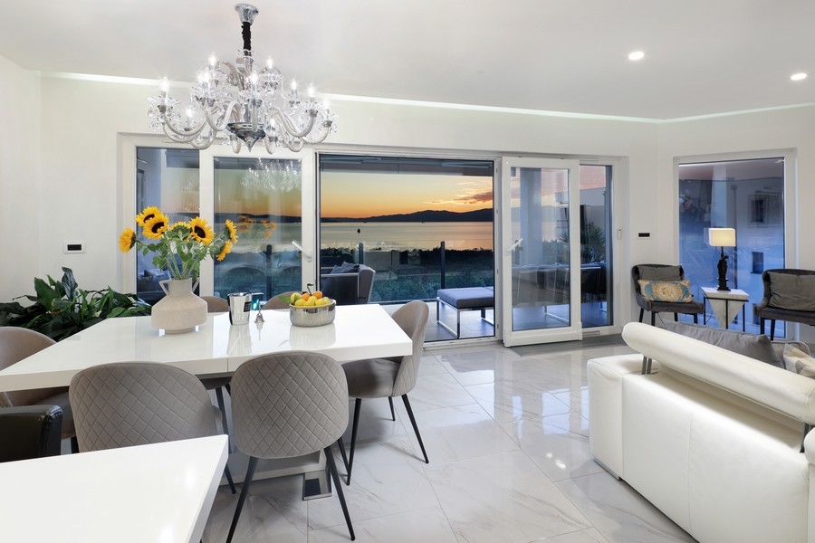 Zona pranzo con lampadario davanti al cielo serale sul mare