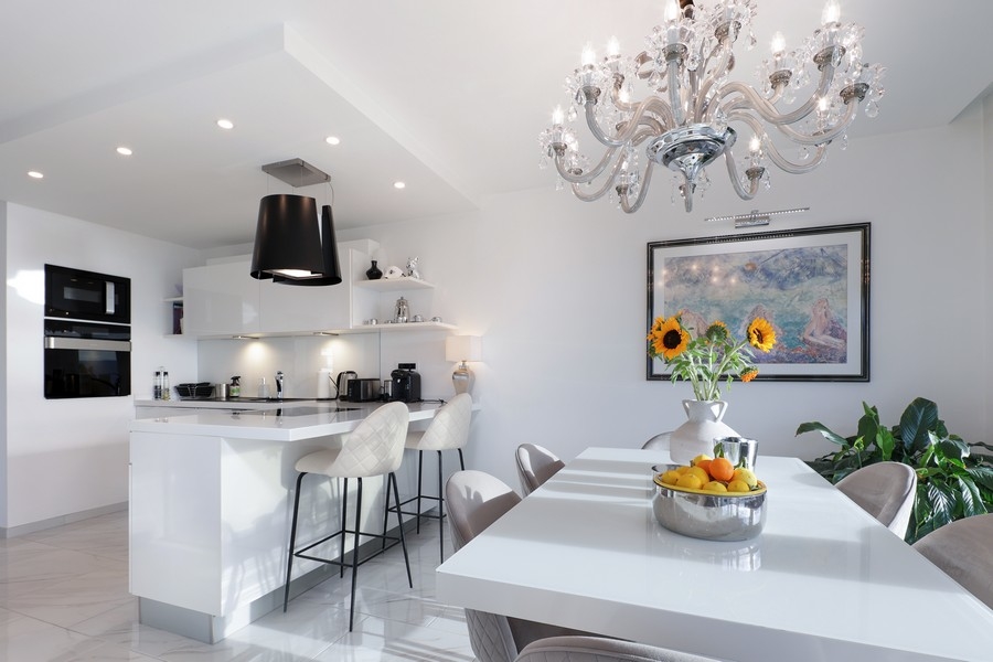 Cucina bianca con isola e lampadario sopra il tavolo da pranzo