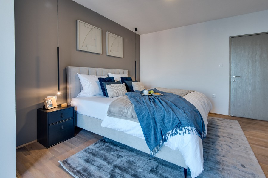 Camera da letto con parete grigia e coperta blu sul letto