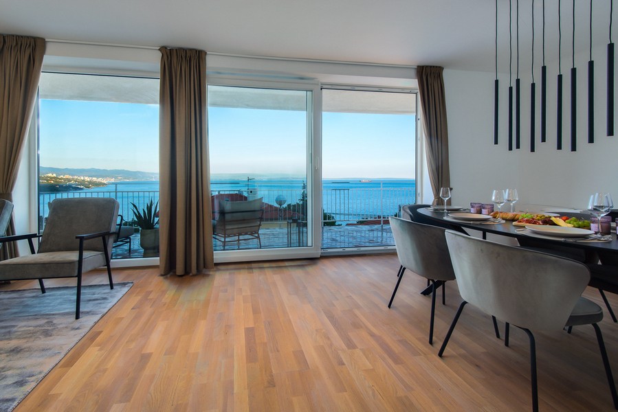Zona giorno con parquet e ampia vetrata sulla baia