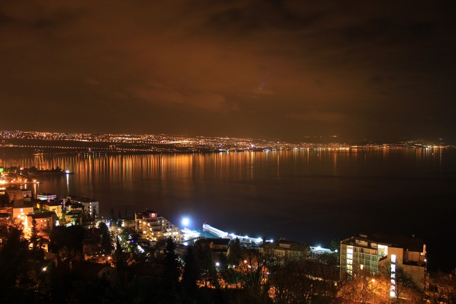 Le luci della costa si riflettono di notte nell'acqua