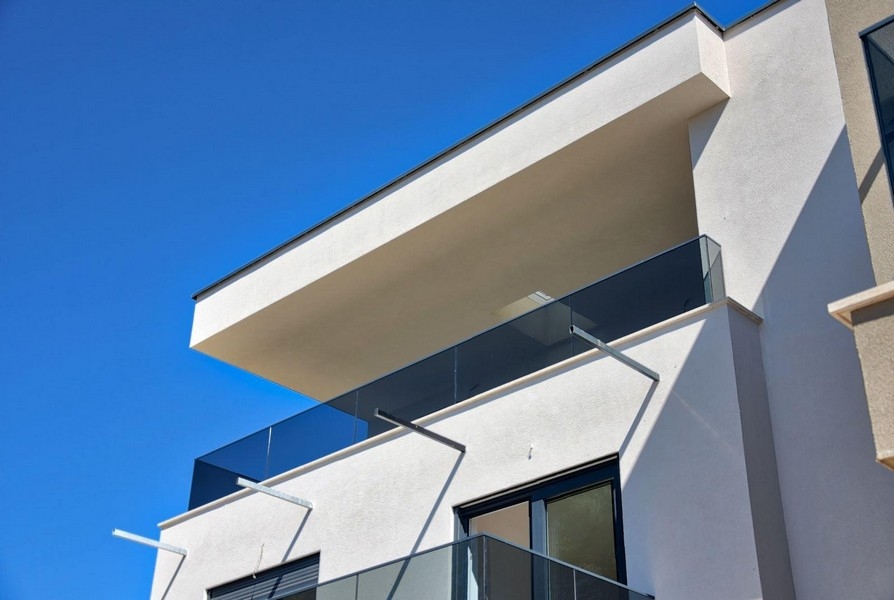 Balcone a sbalzo con parapetto in vetro davanti al cielo azzurro