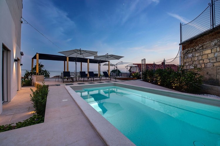 Piscina con ombrelloni e lounge al crepuscolo