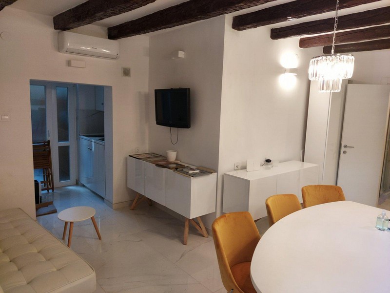 Soggiorno climatizzato con TV, zona pranzo e angolo cottura.