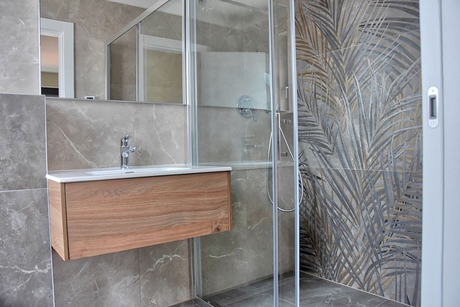 Bagno moderno in un attico in Istria con box doccia con piastrelle di vetro decorative e lavabo in legno.