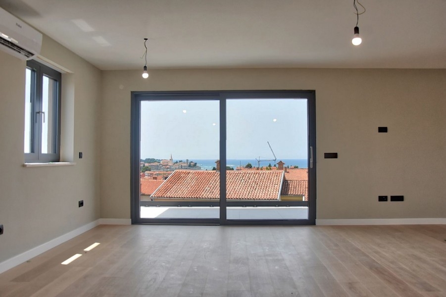 Zona giorno aperta con pavimenti in legno e vista sui tetti istriani, parte di un attico in vendita.