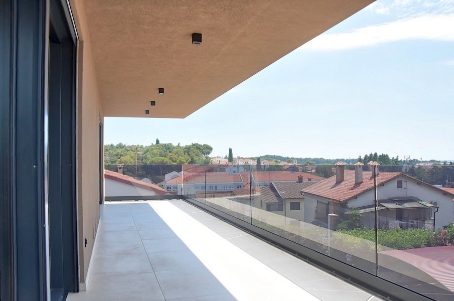 Balcone coperto di un attico in Istria con vista sull'architettura locale e sul mare.
