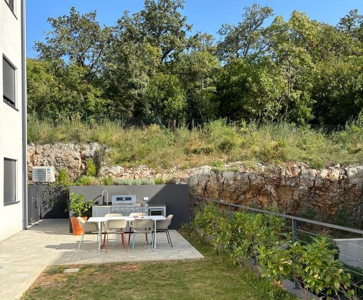 Area giardino con cucina all'aperto e sedute, parte di un appartamento in vendita a Rijeka, Croazia.