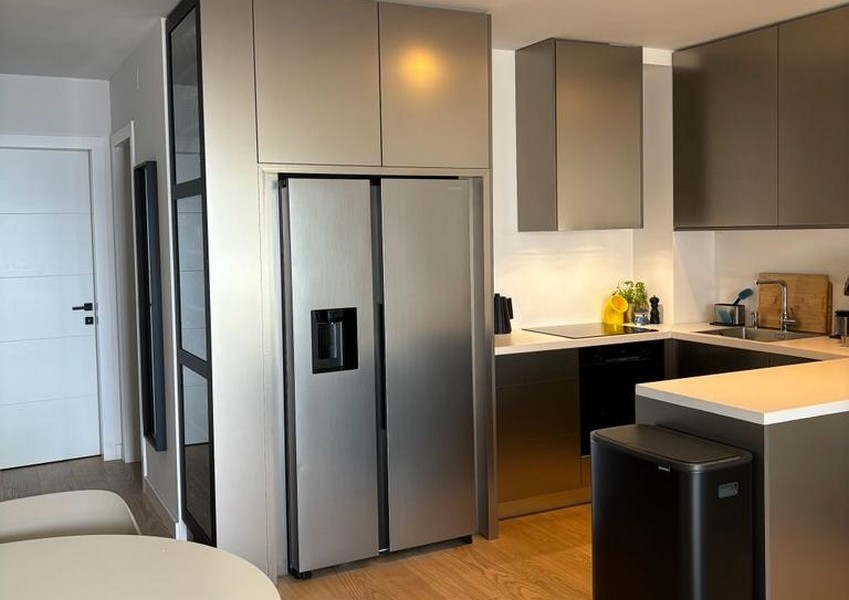 Cucina moderna con frigorifero in acciaio inox e armadi scuri, parte di un immobile a Rijeka, Croazia.