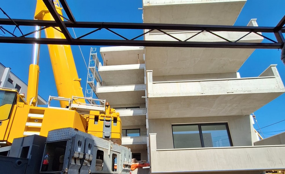 Lavori con la gru alla nuova costruzione di un condominio con balconi