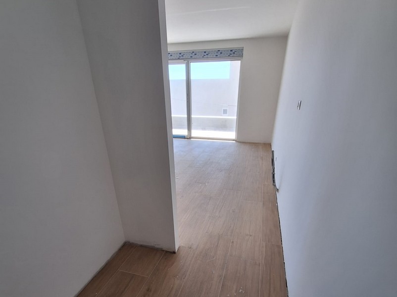 Stanza vuota di nuova costruzione con parquet e porta del balcone