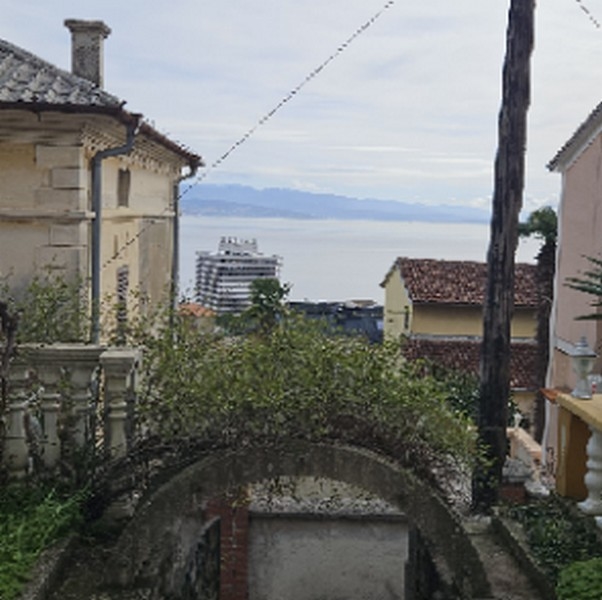 Vista sul mare attraverso un'apertura tra gli edifici con una grande nave in lontananza