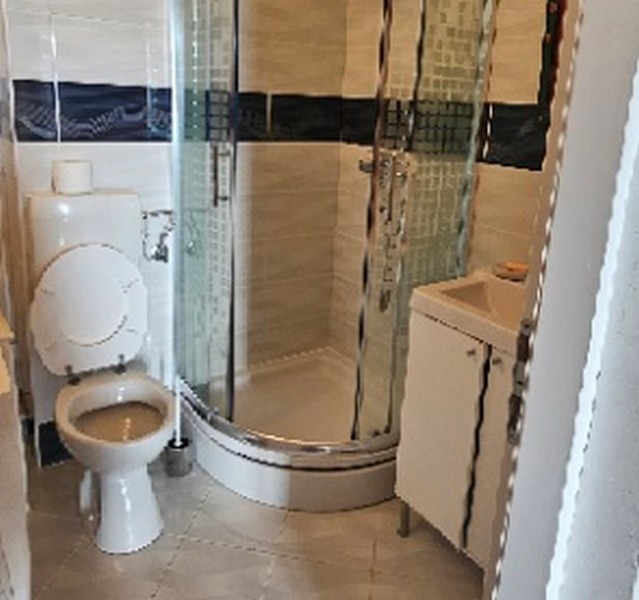 Bagno con box doccia curvo, WC e lavabo in un ambiente piastrellato