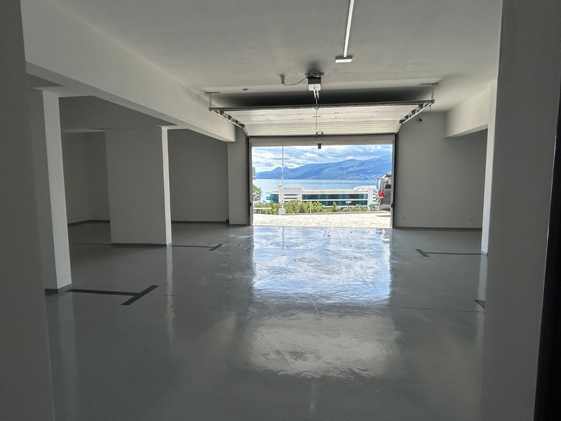 Garage vuoto con pavimento lucido e vista sul mare attraverso il portone aperto a Rijeka, Croazia.