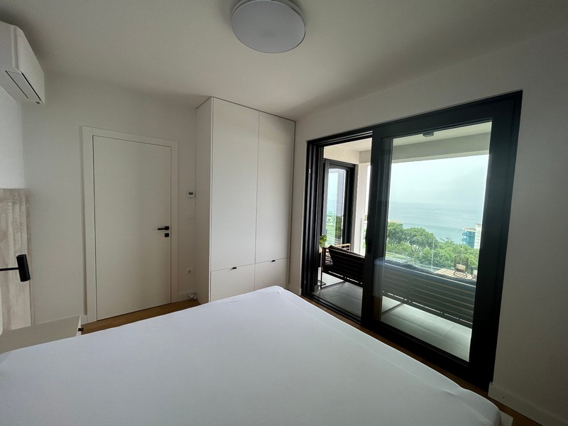 Camera da letto principale in un moderno appartamento con accesso al balcone e vista mare a Rijeka.