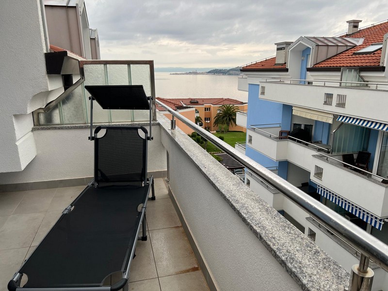 Balcone con lettino e vista sugli edifici vicini fino al mare