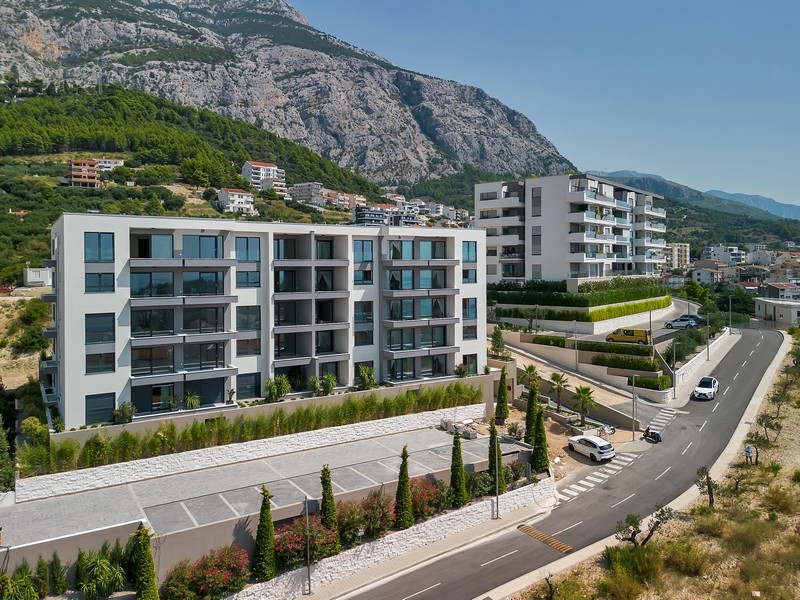 Immobili in Croazia, Makarska, appartamento con vista mare: vista aerea di un moderno complesso residenziale con montagna sullo sfondo