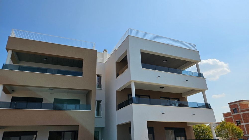 Due edifici nuovi con balconi in vetro e terrazze sul tetto