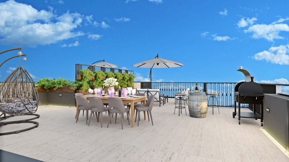 Ampia terrazza sul tetto con vista mare, dotata di tavolo da pranzo, barbecue, piante e sedute sotto gli ombrelloni.