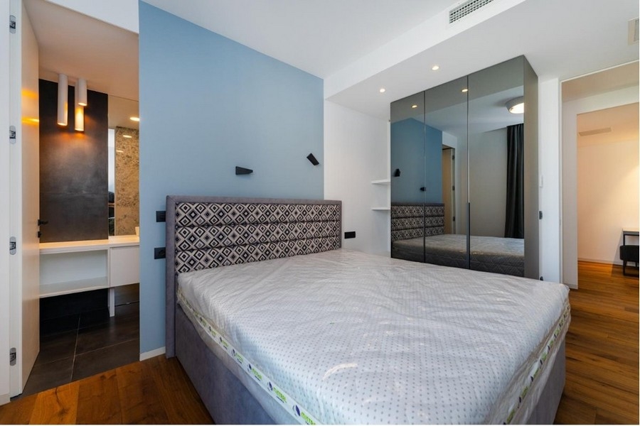 Camera da letto con pareti blu e bianche, letto grigio, armadio con specchio