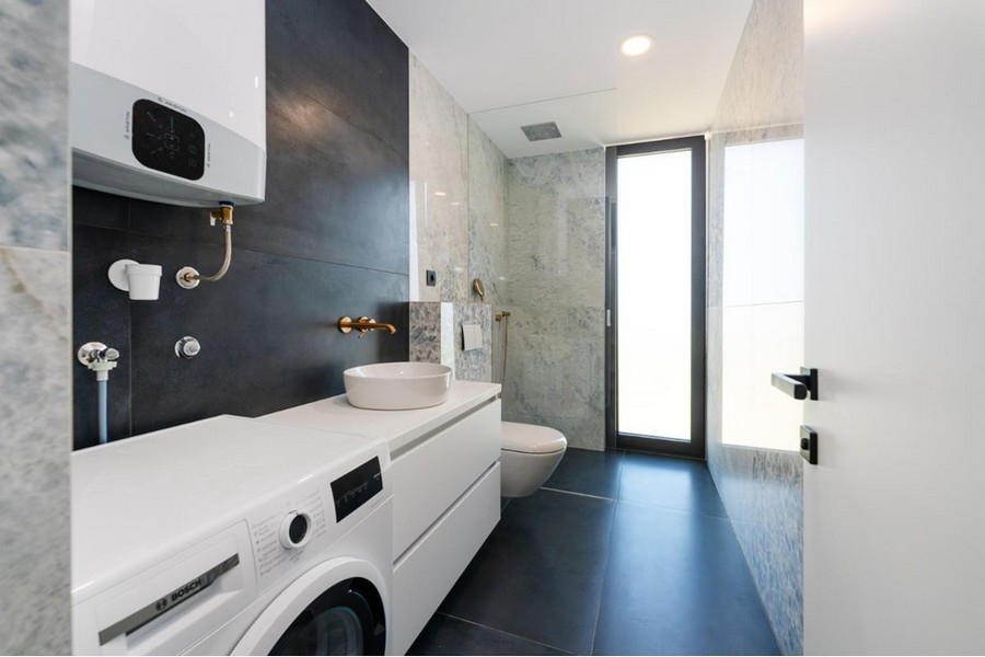 Bagno con lavatrice, lavabo bianco, doccia in vetro