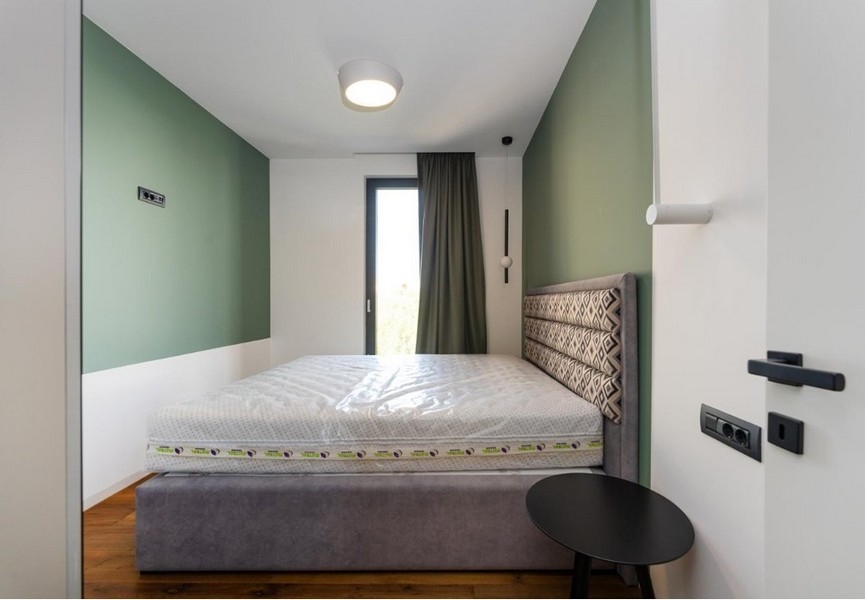 Camera da letto con pareti verdi e bianche, letto grigio
