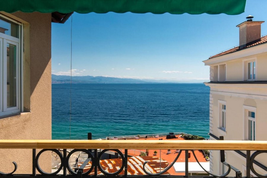 Balcone sotto la tenda verde con vista sull'acqua turchese