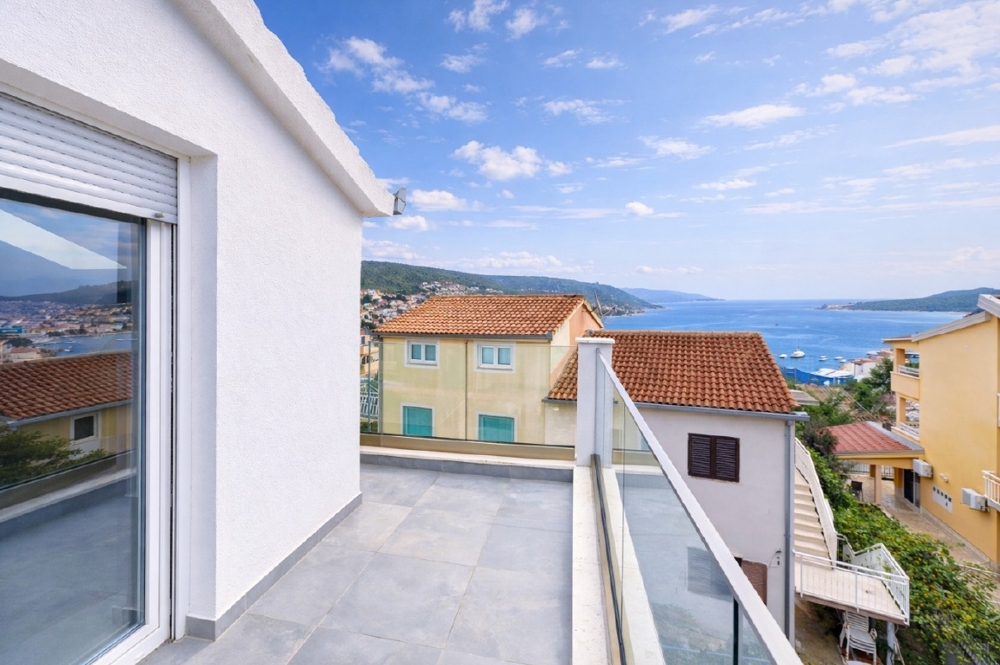 Terrazza sul tetto con parapetto in vetro sopra i tetti di tegole sul mare