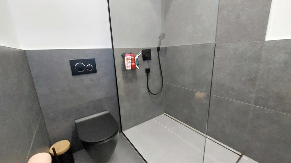 Bagno con doccia a filo pavimento e WC nero