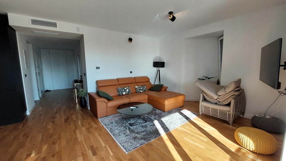 Soggiorno con divano in pelle, parquet e vista sul corridoio