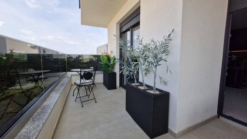 Balcone con mobili da bistrot e piccoli ulivi in fioriera